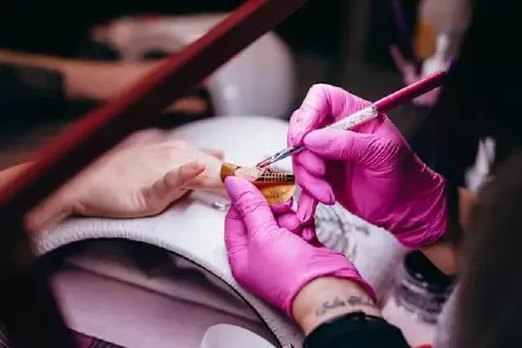 Foto de um procedimento de manicure, focando nas mãos da cliente.